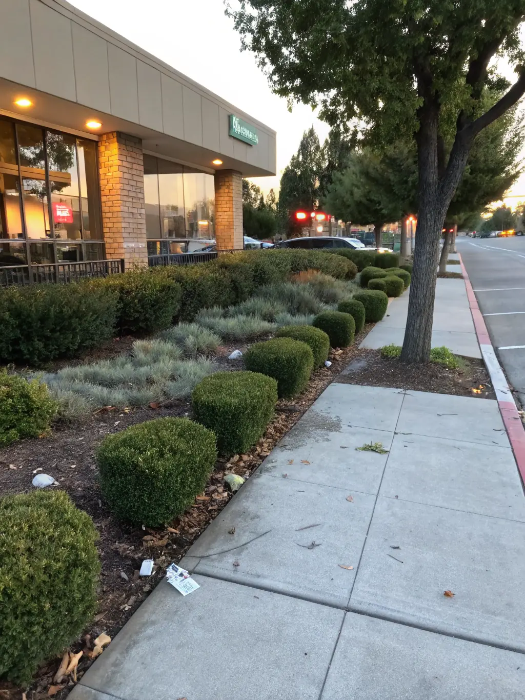 A commercial property being cleaned after hours, with Litter Ghost LLC's team discreetly removing litter. The scene should be quiet and efficient.